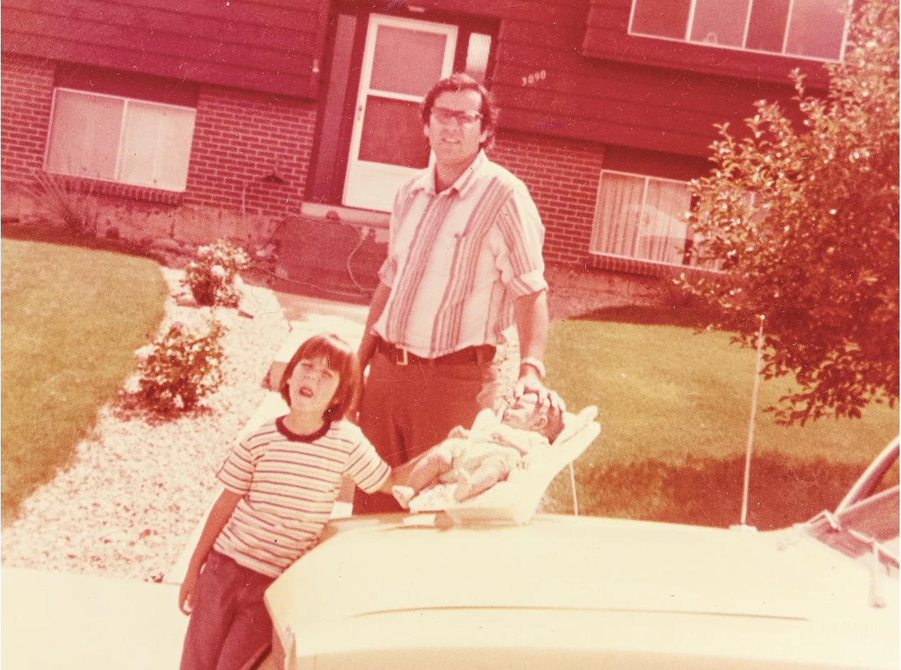 red & sepiatone old photo of a family next to their car